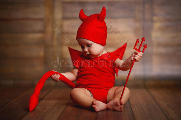 有趣的婴儿在魔鬼万圣节服装在木制背景