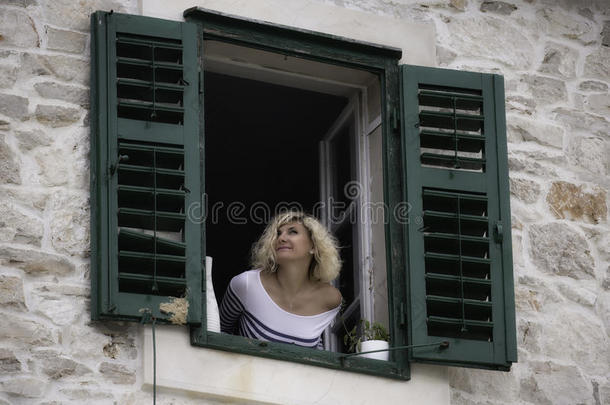 美丽的女人看着窗外，靠在窗台上