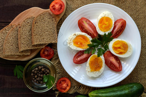 煮鸡蛋和新鲜番茄，黑色面包-清淡饮食早餐。