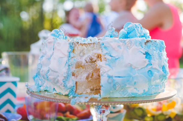 生日蛋糕。 一块已经切好了。 刀子切蛋糕。 在阳光明媚的一天在公园野餐。 蛋糕蓝色和W