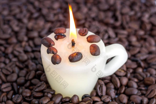 带有温暖火焰的杯子蜡烛和散落的烤咖啡豆