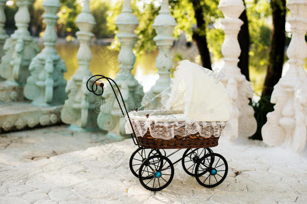 娃娃的婴儿车。 老式娃娃婴儿车放在楼梯上到一个美丽的湖。 复古推车娃娃由藤和白色花边制成。
