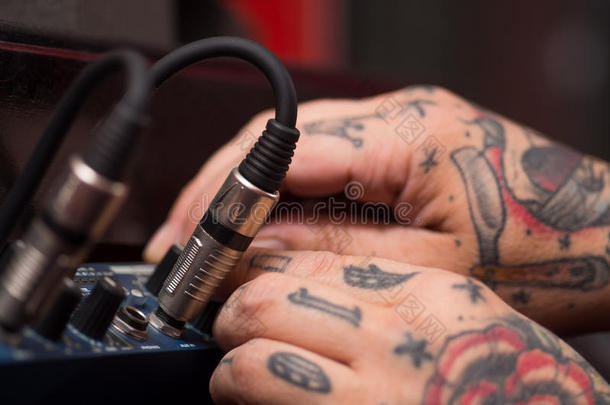 特写的手覆盖纹身工作在电缆连接硬件音频盒，工作室设备的概念