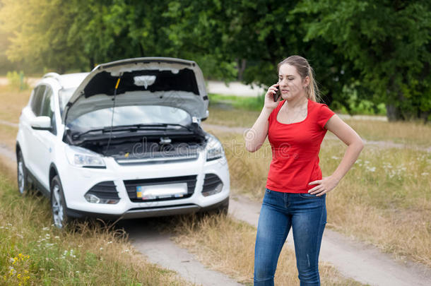 愤怒的女人在草地破碎的汽车旁边呼救