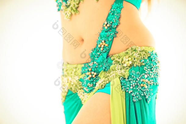 腹部舞者的特写臀部穿着蓝色和绿色的裙子，摆出表演<strong>舞蹈</strong>动作，明亮的<strong>工作室</strong>