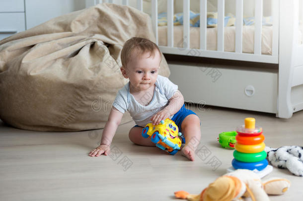 9个月大的小男孩玩玩具车和玩具塔