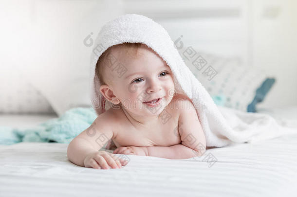 可爱的微笑婴儿戴着头巾，在床上躺着