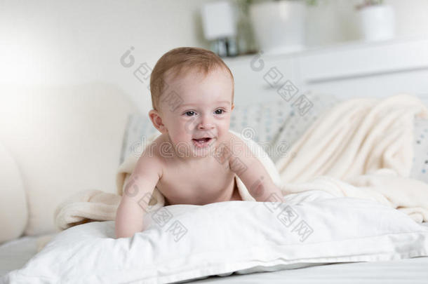 9个月大的婴儿爬在床上的枕头上