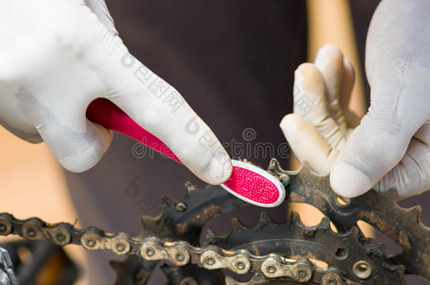 特写手戴白色手套，手持牙刷摩擦金属自行车链，机械维修概念