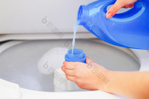 特写妇女的手把洗涤剂倒入测量杯洗衣机，洗衣家务的概念