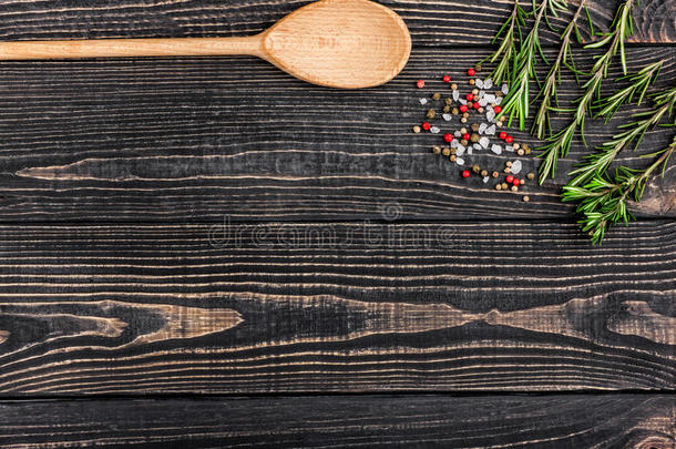 新鲜迷迭香，盐，胡椒和<strong>一个勺子</strong>在黑色的木制背景