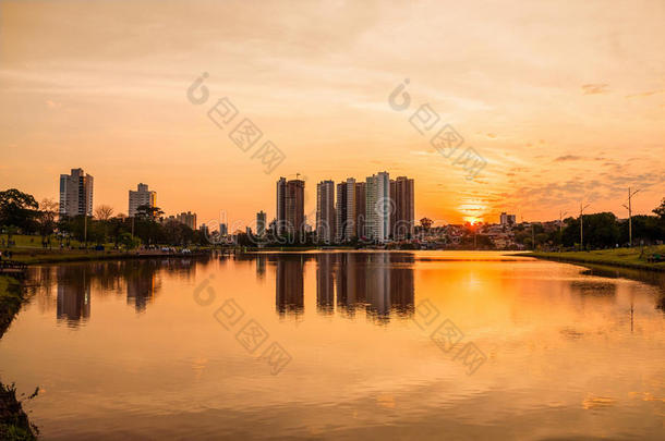 湖上有建筑物和城市背景的美丽温暖的日落。 场景反射在水面上。
