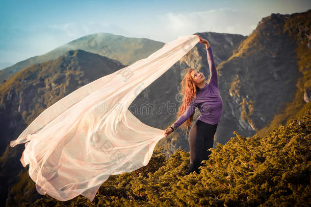 女孩用淡粉色的布料在山上玩风