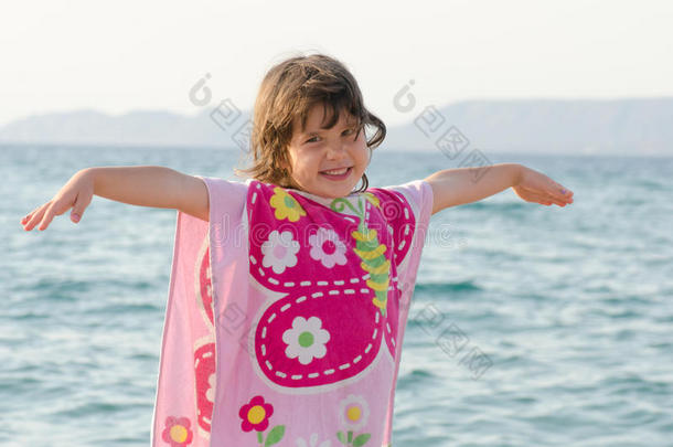 美丽的小女孩穿着粉<strong>红色</strong>的蝴蝶毛巾在<strong>海边</strong>微笑