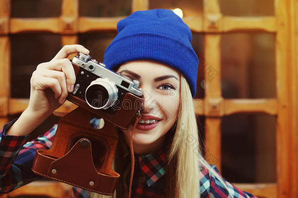 特写照片，时尚，快乐，微笑，时髦的女孩在支架与老式光电相机。 模特看相机