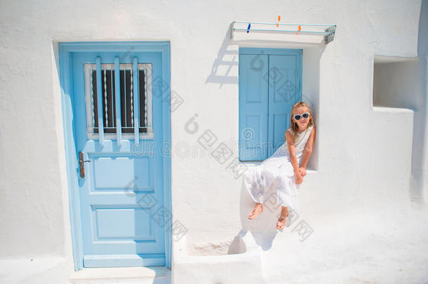 迷人<strong>的</strong>女孩穿着白色连衣裙，在户外<strong>的</strong>旧<strong>街道</strong>上，穿着米科诺斯。 典型<strong>的</strong>希腊传统村庄<strong>的街道</strong>上<strong>的</strong>孩子
