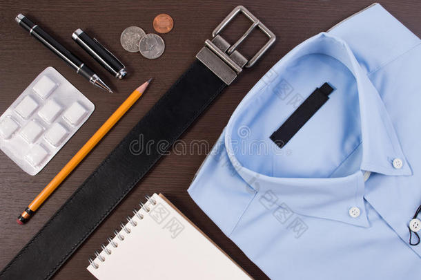 商务衬衫休闲装和配件带与钢笔和口香糖在木制桌子上。
