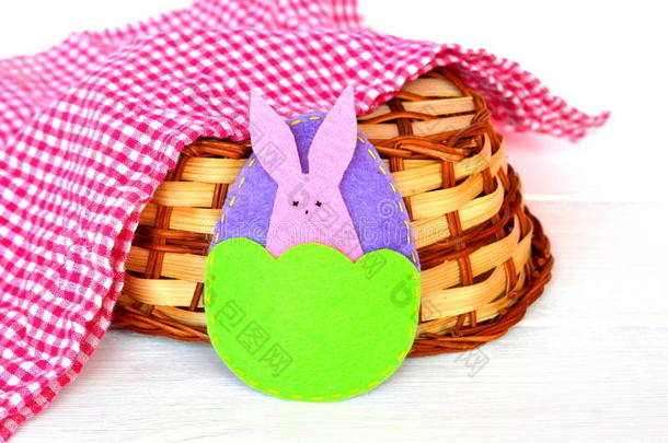 复活节彩蛋和兔子，篮子，白色木制背景上的毛巾。 毡制工艺品