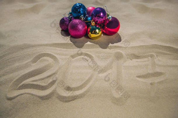 圣诞彩球躺在海滩上，在沙子旁边，日期是写的。