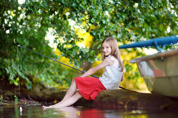 可爱的小女孩在河边用钓竿钓鱼