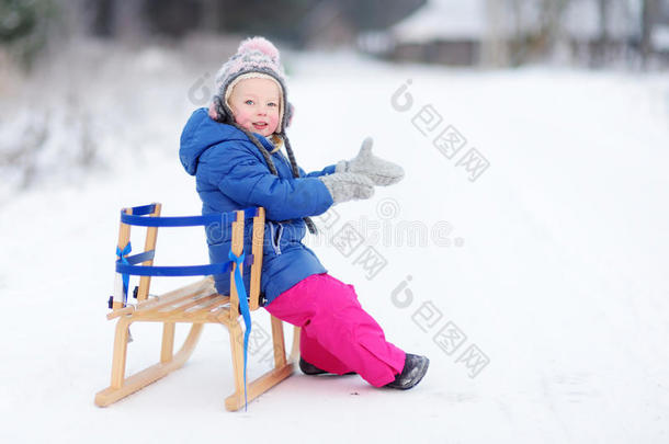 有趣的小女孩在冬天的公园玩雪橇