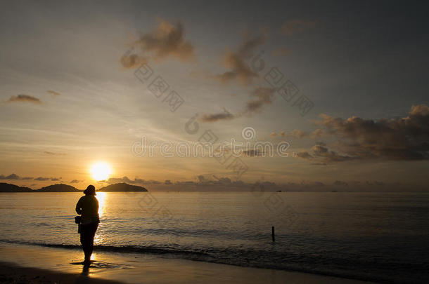 渔夫在日出时在海滩上寻找贝壳