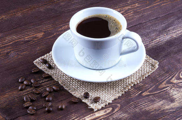 杯子里的黑咖啡和茶托<strong>咖啡豆散落</strong>在一起