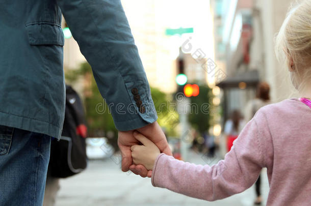 父亲牵着女儿/孩子的手在红绿灯后面