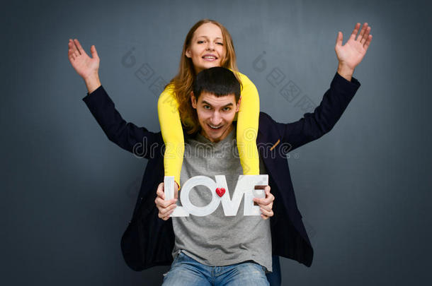 美丽的微笑的夫妇抱着爱的话语，站在灰色的背景上