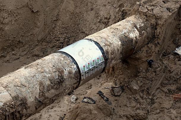 挖掘坑。 旧的饮用水管道与不锈钢修复套筒成员。