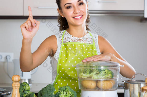 开朗的女孩在蒸笼里煮蔬菜
