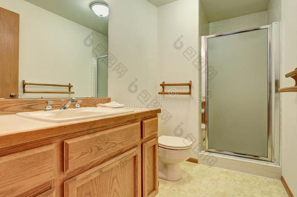 浴室内部有木制梳妆台，大镜子和瓷砖地板。