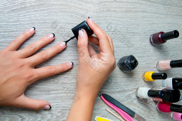 黑色指甲油被应用于手与工具的指甲在背景上。 美丽的过程。 上面的风景。 复制空间