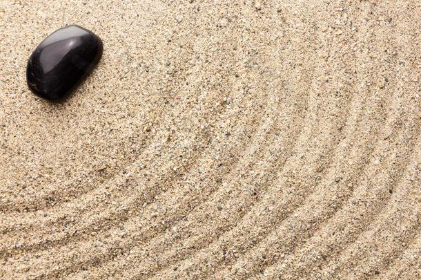 沙子上的黑色玄武岩石头模仿水的涟漪