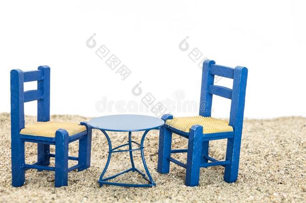 蓝色油漆椅子和桌子在沙子上，白色背景。