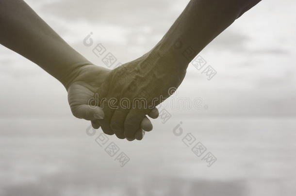亲密的手，老年夫妇牵着手在海边附近的海滩，<strong>黑白图片</strong>的颜色