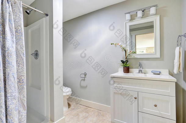 可爱的浴室内部与白色梳妆台，瓷砖地板和漂亮的浴帘。