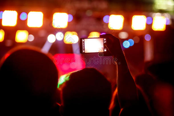 男孩用智能手机拍照片去音乐会，分享社交网络上的朋友