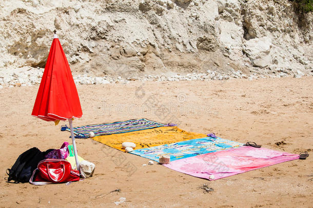 海滩毛巾和红色雨伞在海边的沙滩上