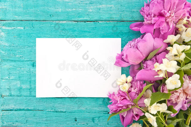 一束粉红色的牡丹花和<strong>仿</strong>橘红色的花，绿松石色的乡村<strong>木纹</strong>背景，上面有一张空卡片，用来打招呼。