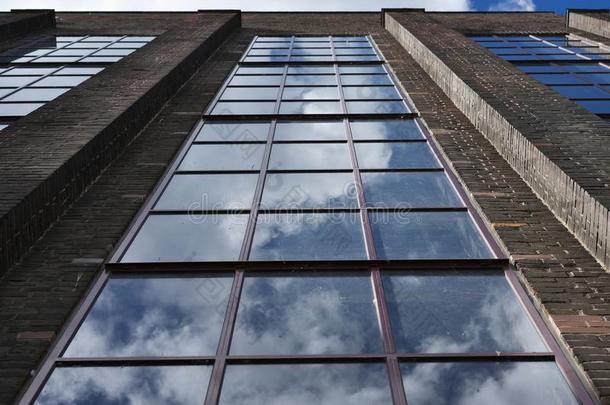 工厂砖墙上大而长的窗户的详细图片，云彩和天空。