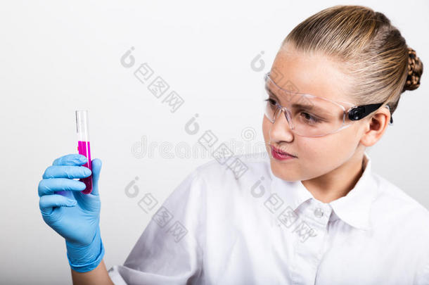 穿着医用衣服的特写小女孩。 专心的女学生在小学科学上做化学实验
