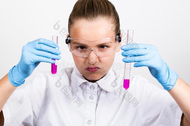穿着医用衣服的特写小女孩。 专心的女学生在小学科学上做化学实验