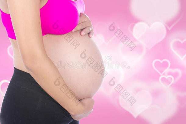 孕妇腹部的特写，她的手放在心脏ba上