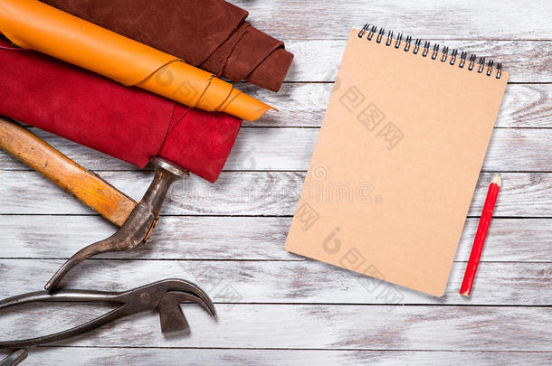 色彩鲜艳的皮革卷，工作工具，鞋持久，笔记本与铅笔在白色背景。 皮革工艺。