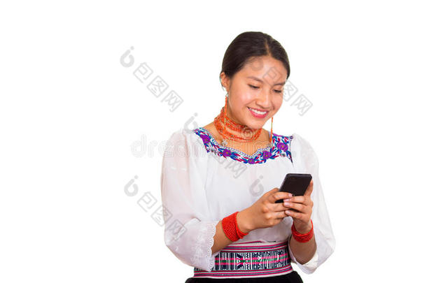 美丽的年轻女人站着，穿着传统的安第斯衬衫和红色项链，拿着手机发短信