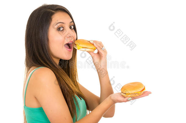 美丽的年轻女人摆着<strong>姿势</strong>，准备<strong>拍照</strong>，一边吃汉堡包，一边拿着另一只手，开心地笑着，白色的