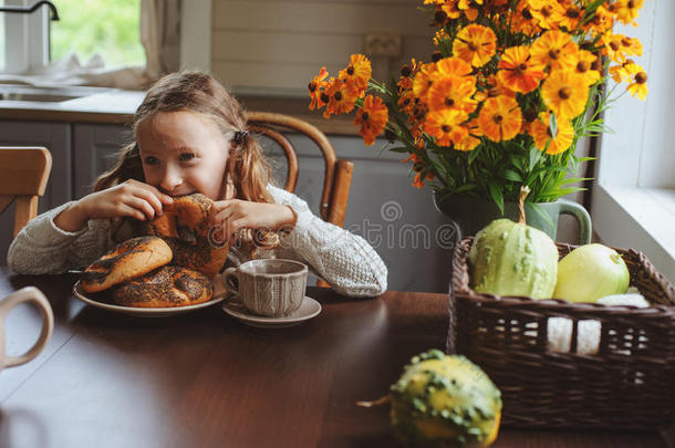 秋天的早晨在家吃早餐的小女孩。乡村住宅的真实生活舒适现代室内设计