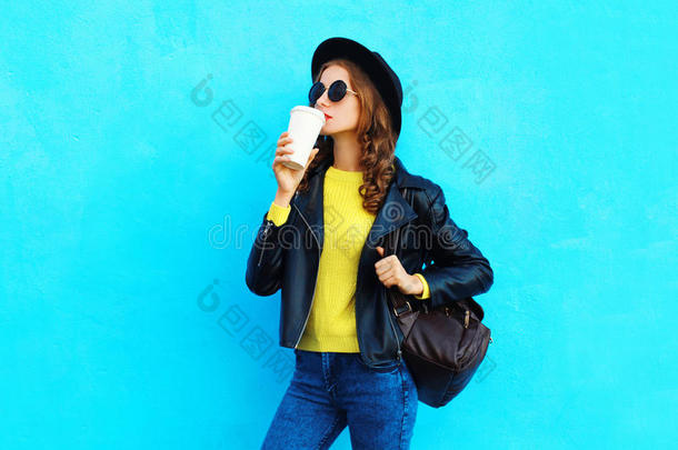 时尚漂亮的年轻女人带着咖啡杯，穿着黑色的摇滚风格的衣服，穿着五颜六色的蓝色