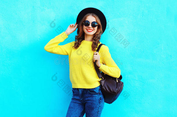 <strong>时尚</strong>漂亮的微笑女人戴着<strong>黑</strong>色帽子，黄色针织毛衣和背包，上面有<strong>五</strong>颜六色的蓝色